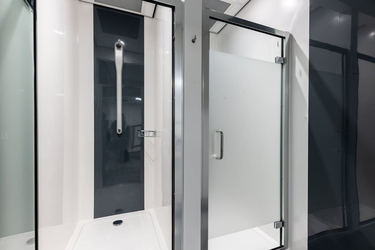 PureGym Glasgow Milngavie: Shower rooms with glass doors, tiled floors, and grab bars.