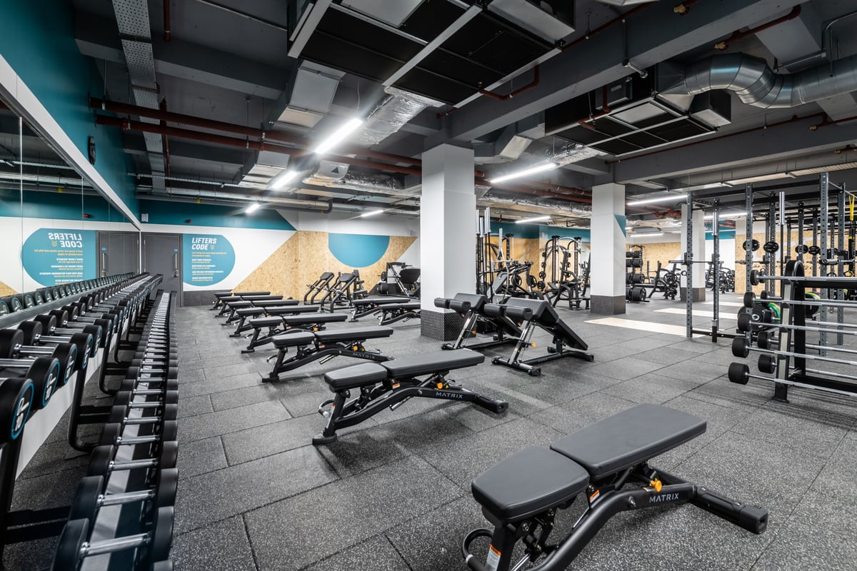 PureGym London Kingston: Rows of benches, weightlifting equipment, dumbbells, and rubberized gym flooring.