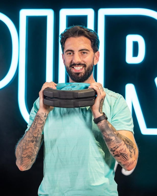 Mann hält eine Gewichtsplatte vor einem leuchtenden Fitnessstudio-Schild