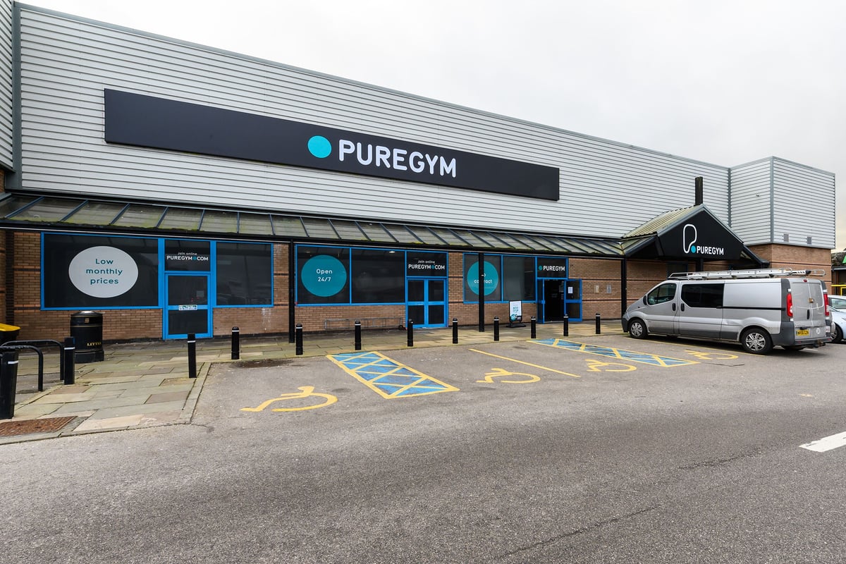 PureGym Bromborough: Exterior of a gym building with signage, parking spaces marked on ground.