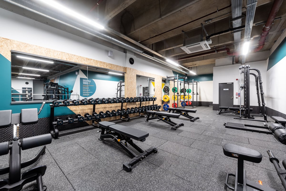 PureGym London Ealing Broadway: Rows of free weights, benches, weight racks, and rubberized flooring in a gym studio space.