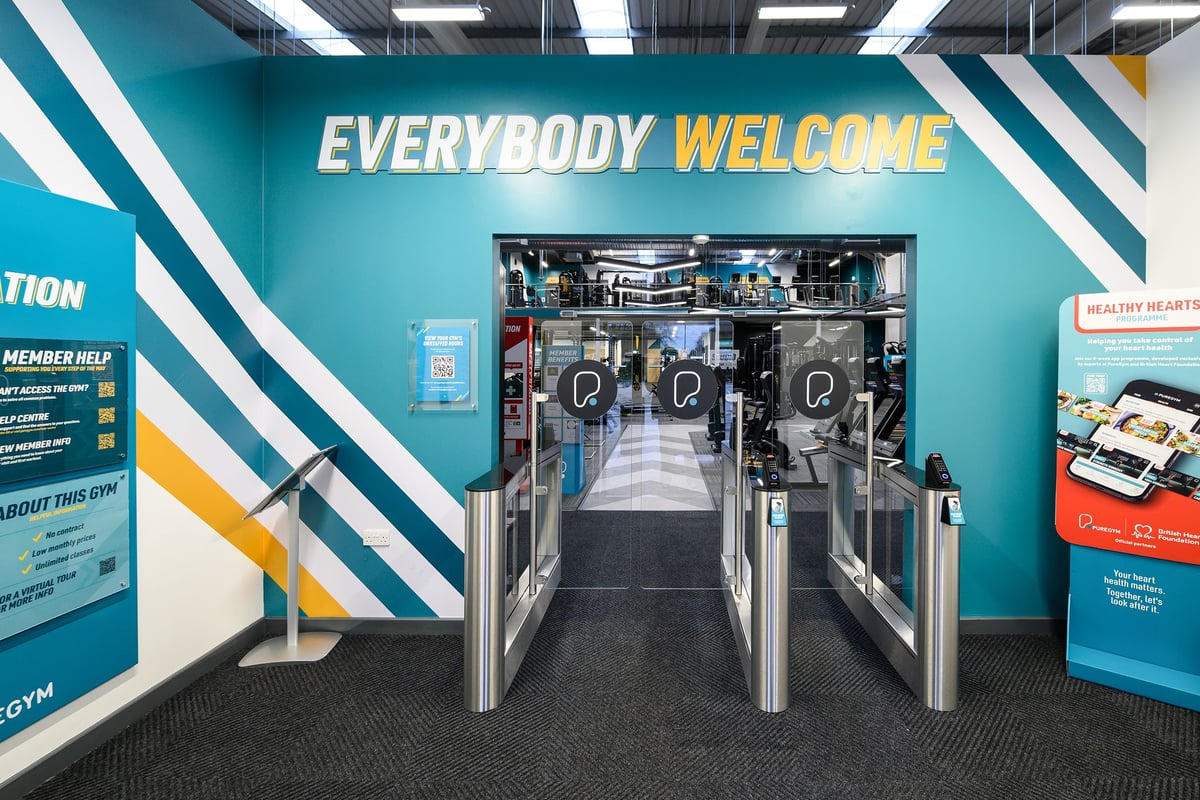PureGym South Ruislip: Turnstiles, cardio machines visible through entrance corridor, "Everybody Welcome" signage.