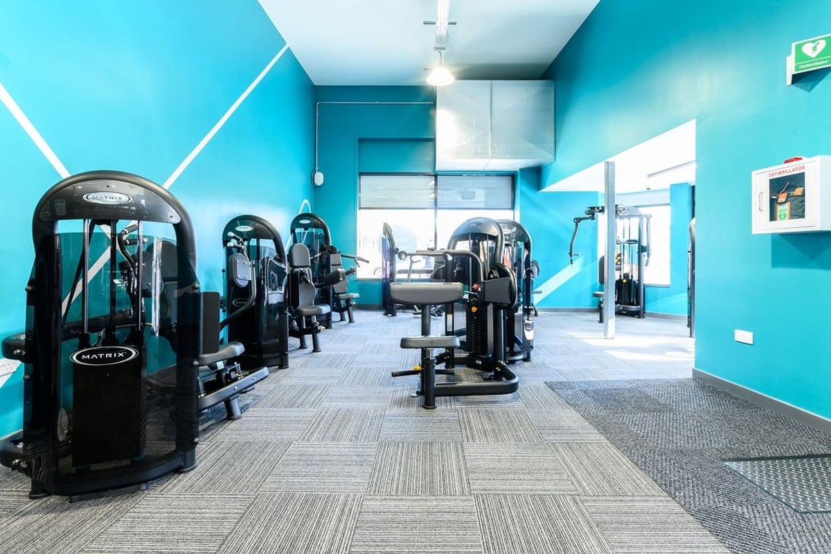 PureGym Bath Spring Wharf: Gym studio containing rows of cardio machines, with teal walls and patterned flooring.