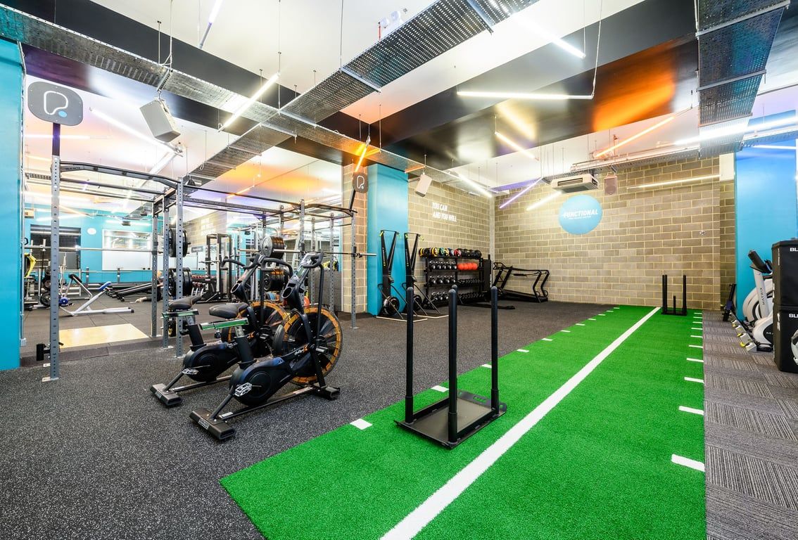 PureGym London Borough: Treadmills, weight racks, turf training area, resistance machines in modern fitness studio.