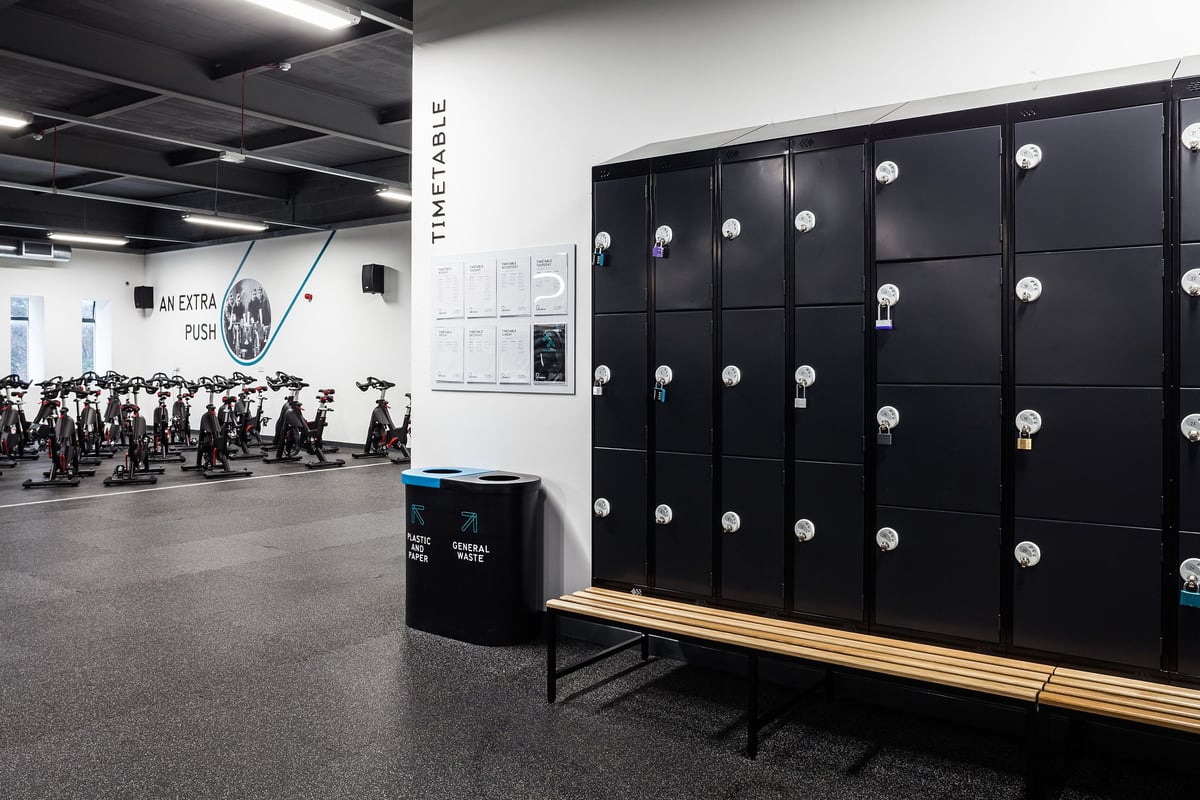 PureGym Manchester Stretford: Rows of lockers, benches, and strength training logos on the walls.