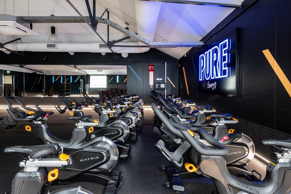 PureGym London Marylebone: Rows of futuristic cycling machines in a dimly lit studio with blue accent lighting.