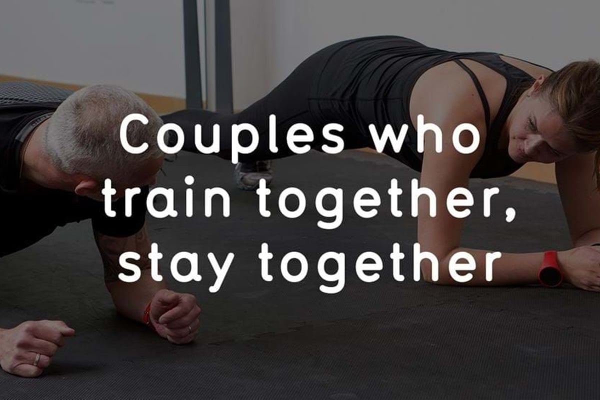 Couple doing plank exercise side by side on a gym mat indoors