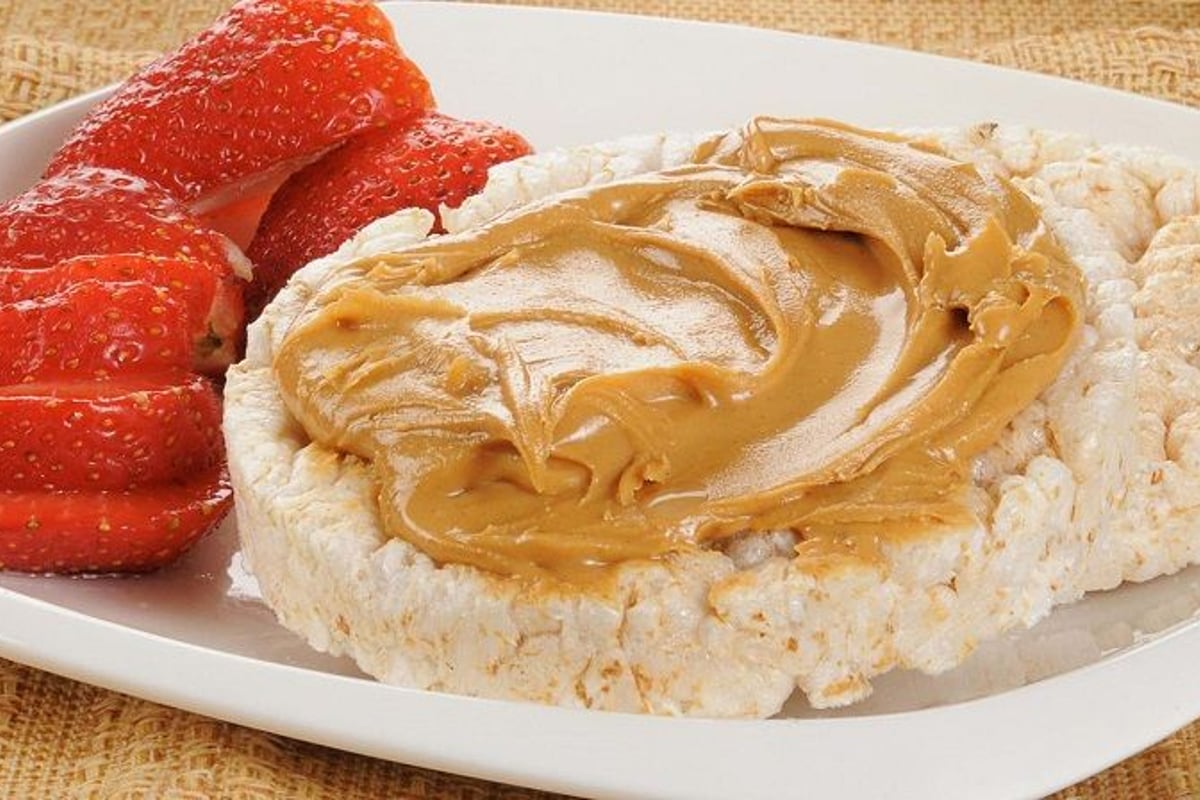 Rice cakes with peanut butter and sliced strawberries on a white plate