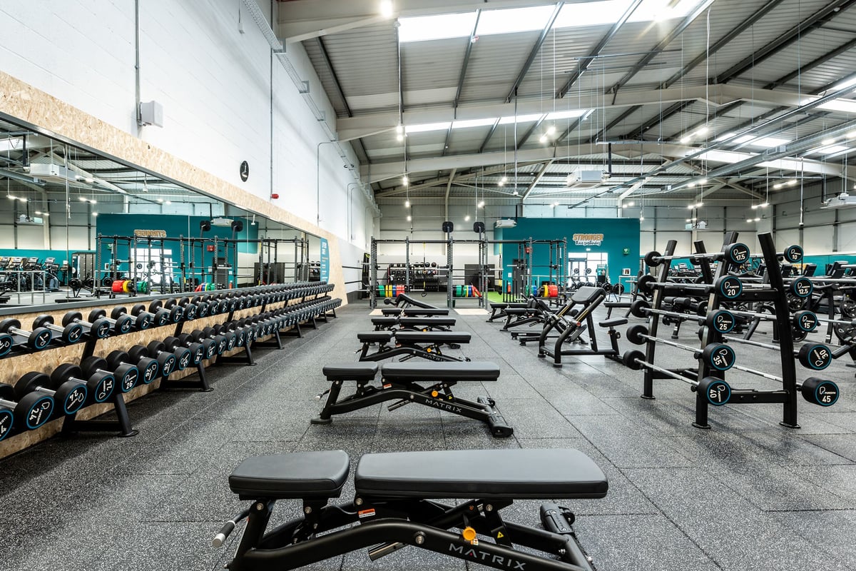 PureGym Newbury: Rows of weightlifting benches, squat racks, free weights, and rubberised flooring in a gym space.
