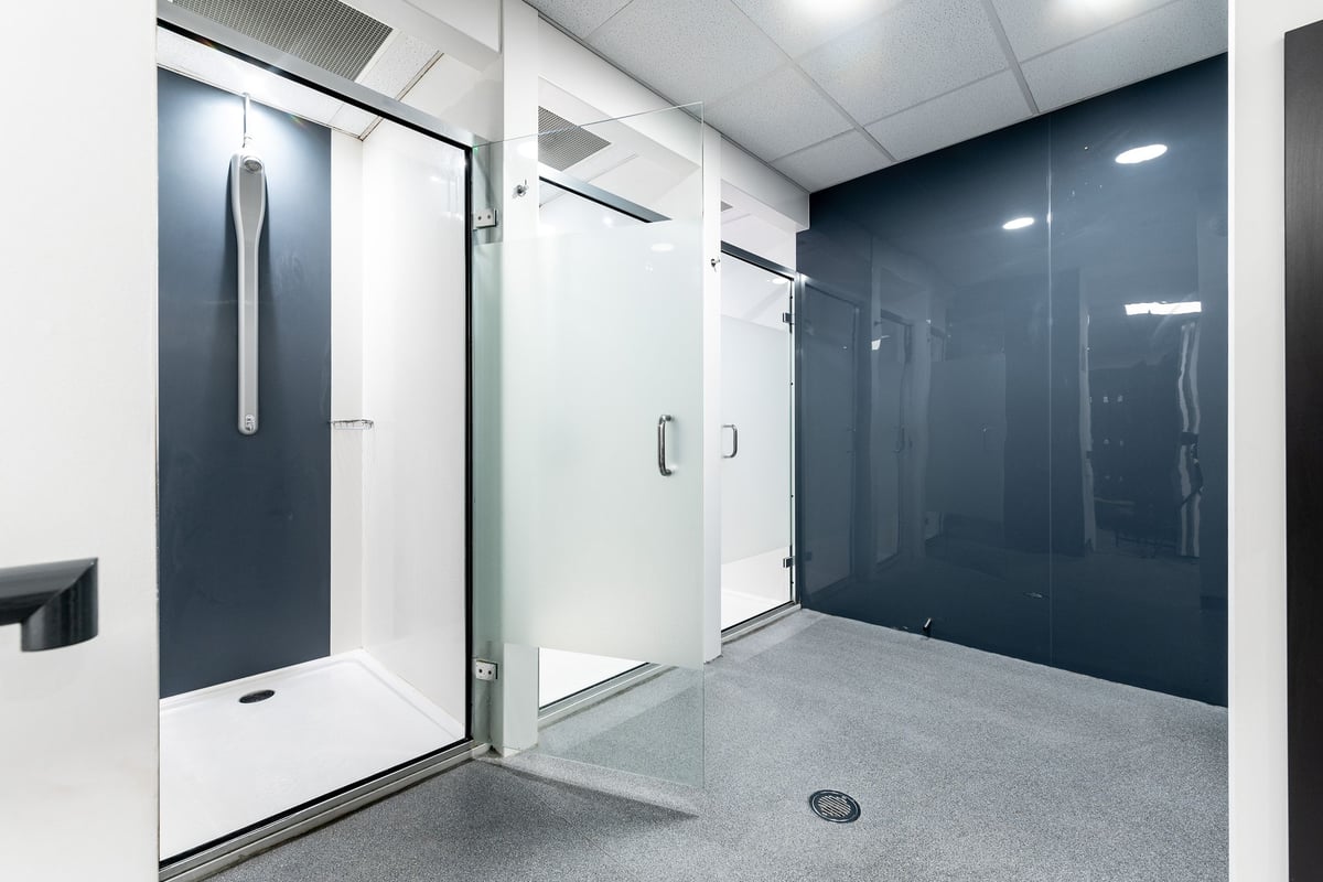 PureGym London Camberwell New Road: Shower room with frosted glass shower enclosures, floor drain.