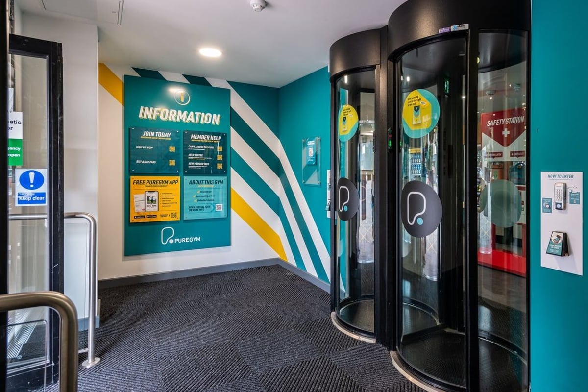PureGym Northwich: Revolving doors, information signage, and a teal-accented interior space.
