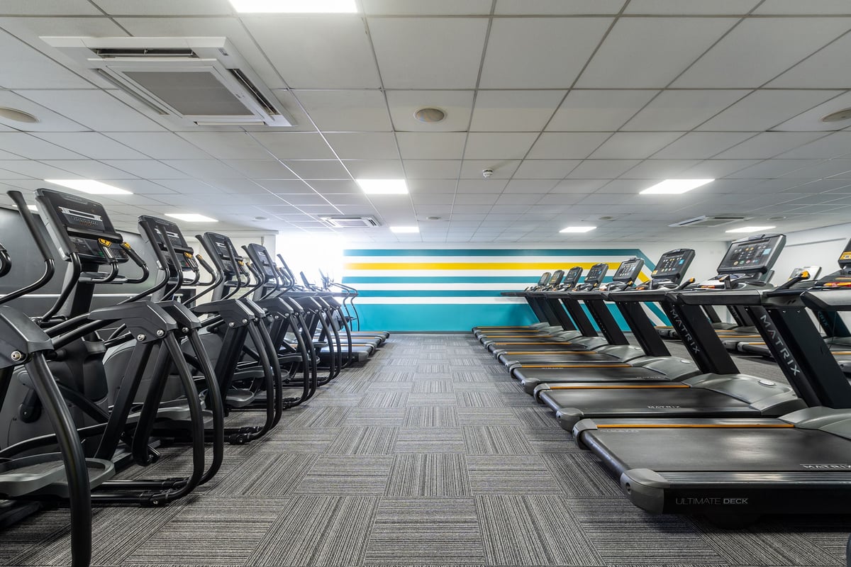 PureGym Sutton Coldfield: Rows of treadmills facing a mirrored wall in a brightly lit gym space.