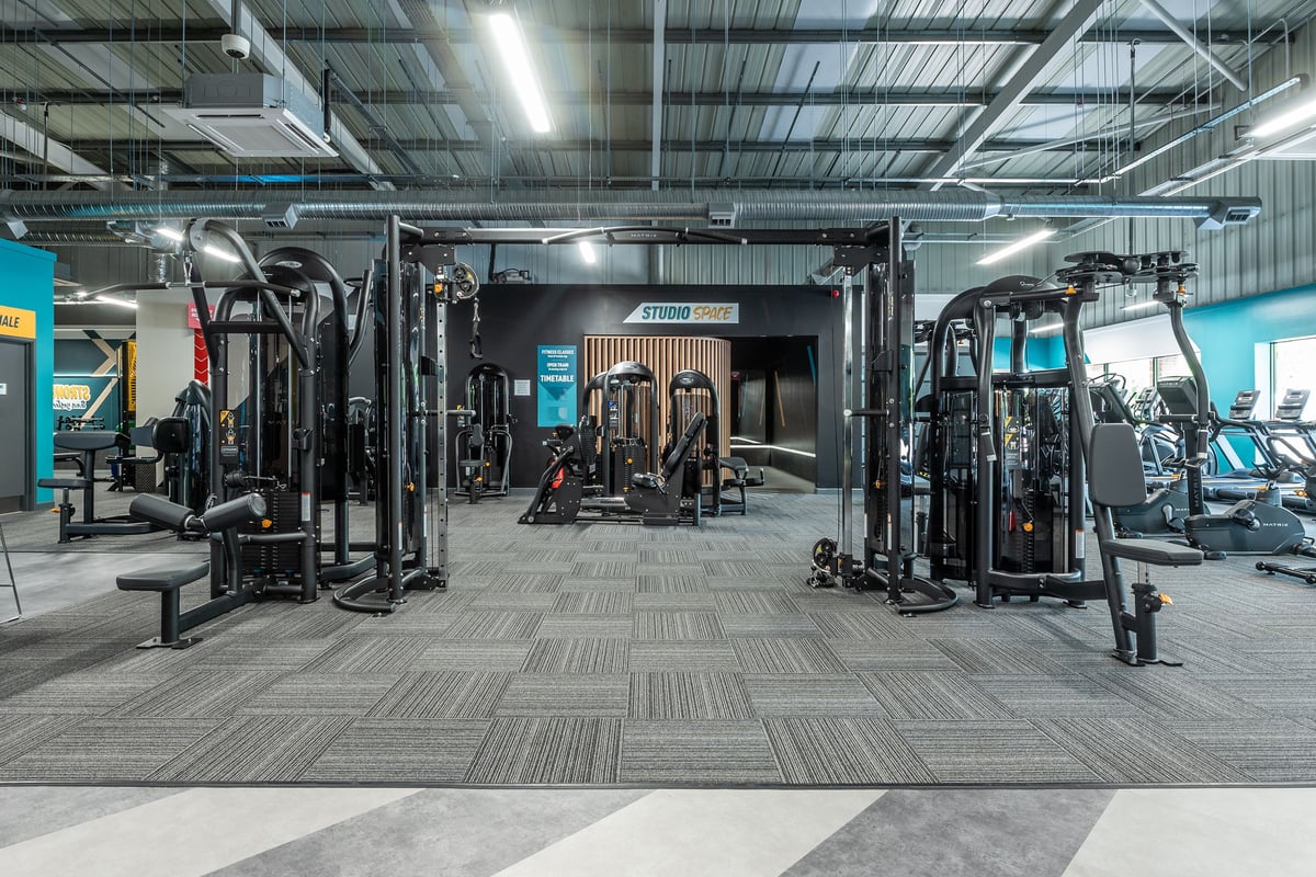 PureGym Horsham: Weight machines, cable crossovers, squat racks, benches, rubberized flooring in a gym facility.