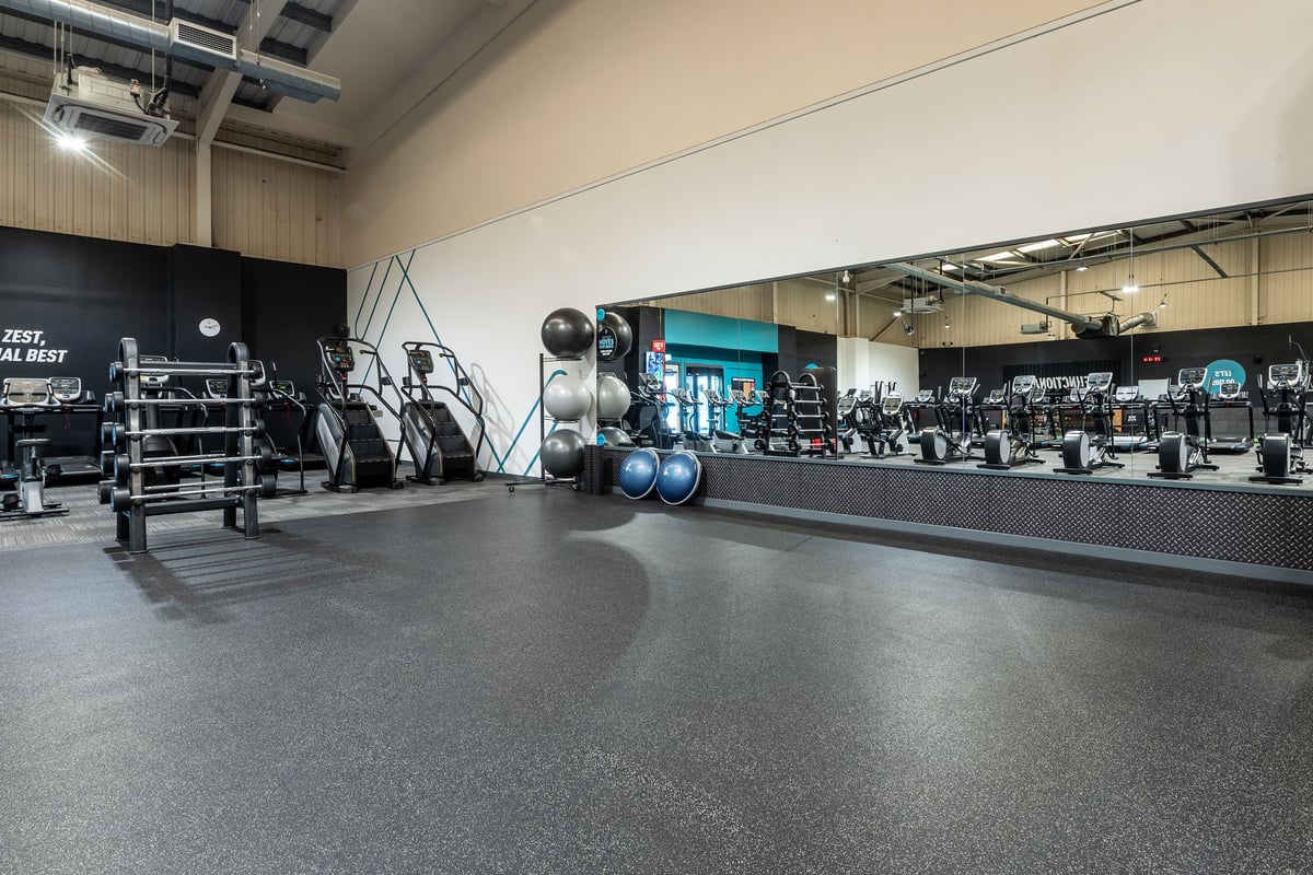 PureGym Weston-super-mare: Gym space with racks, weight plates, medicine balls, rubberized flooring, and mirrored walls.