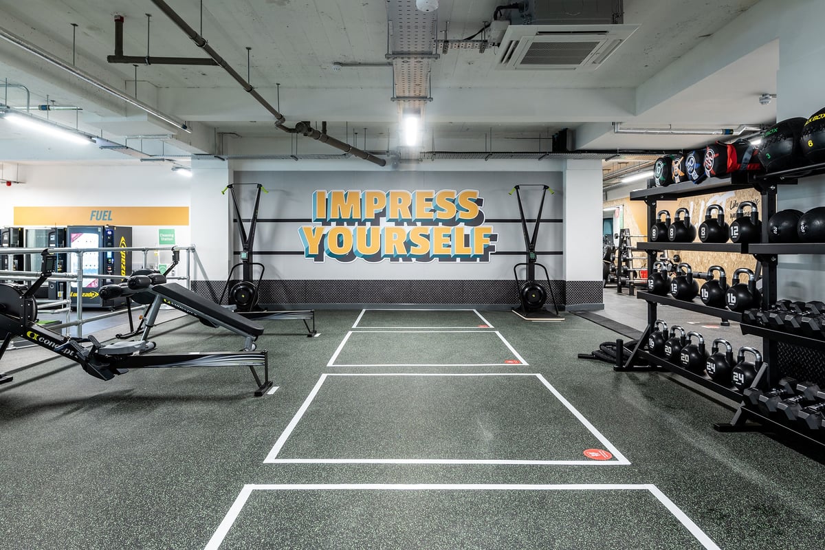 PureGym London Holloway Road: Gym studio with sled tracks, resistance machines, weight racks, and motivational wall signage.