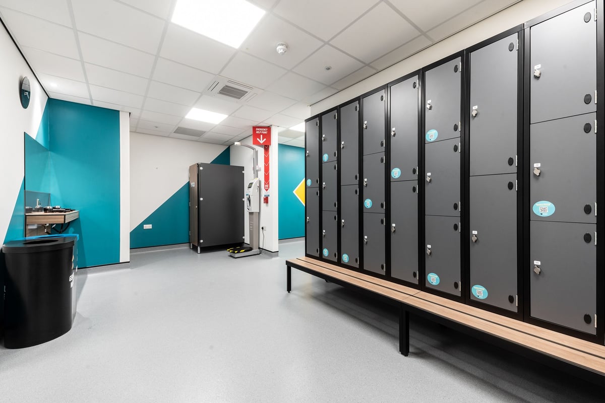 PureGym Barnsley: Rows of lockers, benches, turquoise walls, and trash bins.