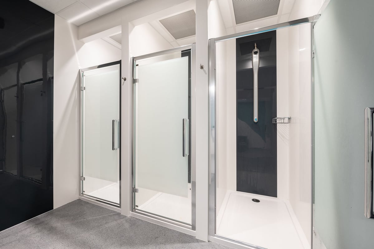 PureGym Craigavon: Shower stalls and changing rooms with frosted glass doors and benches.