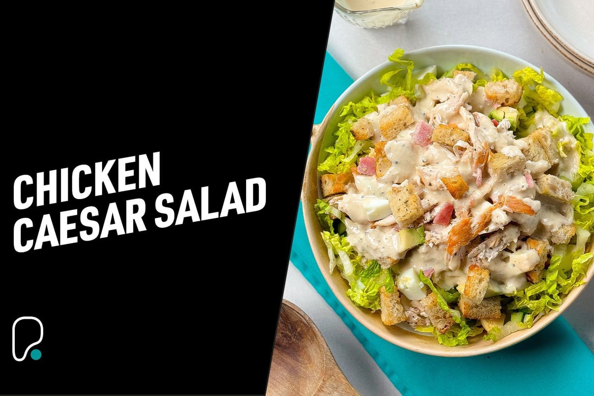 Chicken Caesar salad with lettuce, croutons, chicken pieces, and creamy dressing in bowl