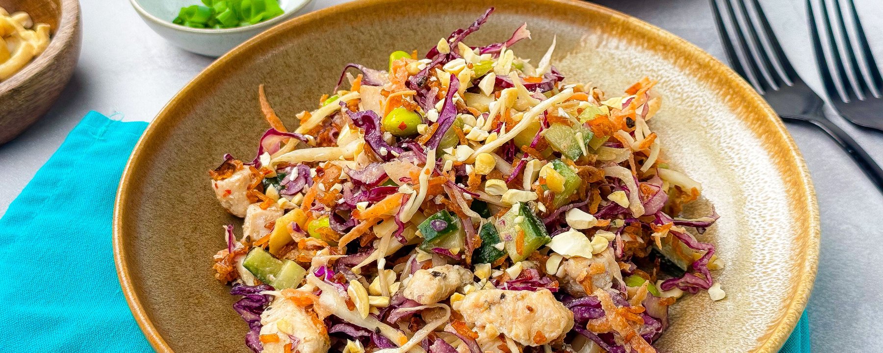Colourful salad with shredded cabbage, carrots, chicken and nuts on a ceramic plate