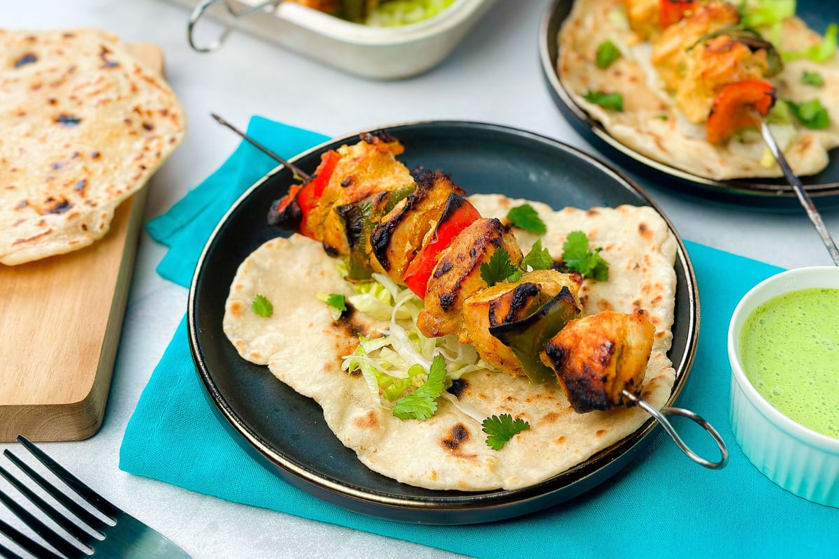 Grilled chicken and vegetable skewers served on flatbread with shredded lettuce and herbs