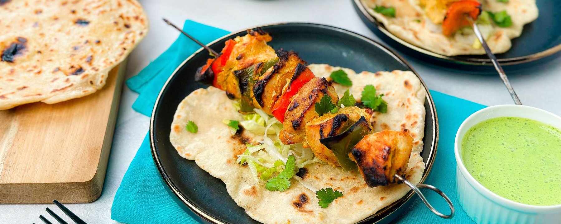Grilled chicken and vegetable skewers served on flatbread with shredded lettuce and herbs
