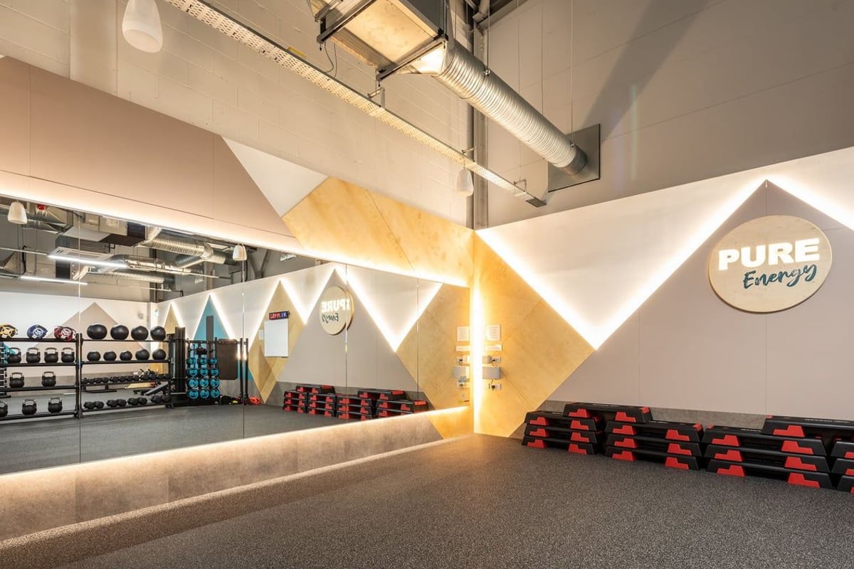 PureGym Wantage: Weight racks, kettlebells, rubberised flooring, geometric wall designs with 'PURE Energy' branding.