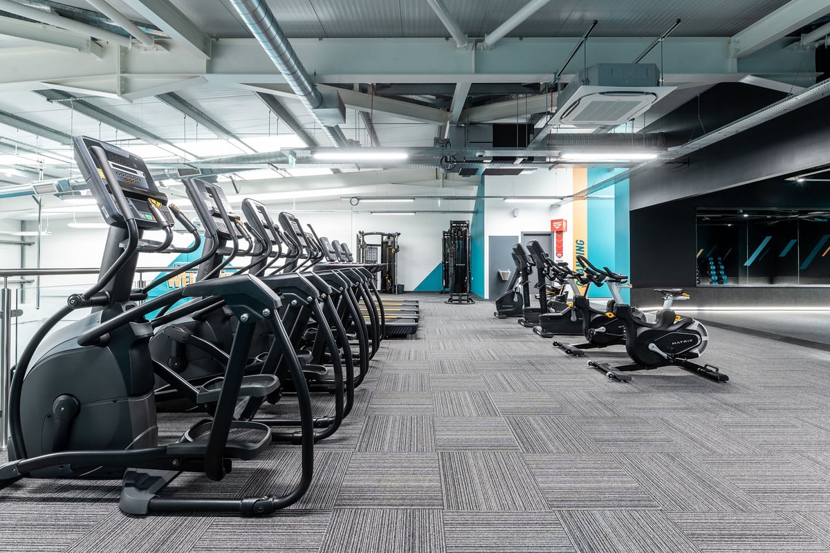 PureGym Ormskirk: Rows of elliptical machines, treadmills, and weight racks inside a brightly lit gym space.