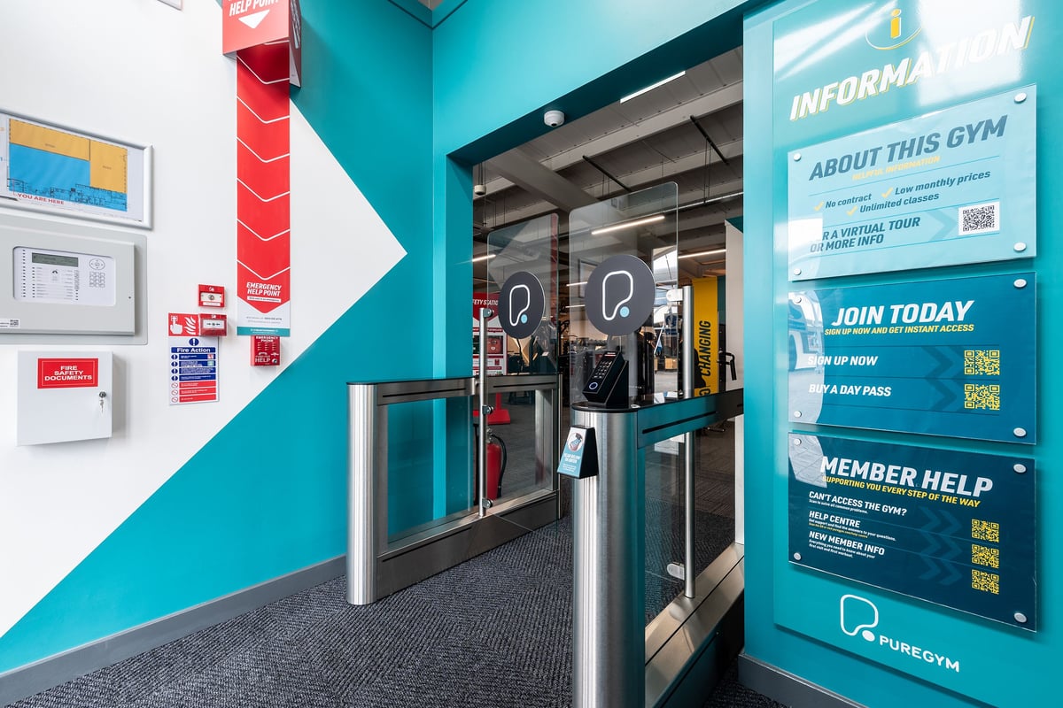 PureGym Bideford: Turnstiles, membership signs, and gym entrance area with teal walls.