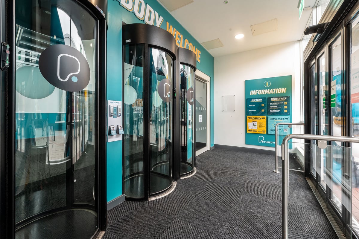 PureGym Loughborough: Entry pods and information signage in a teal and grey reception area.