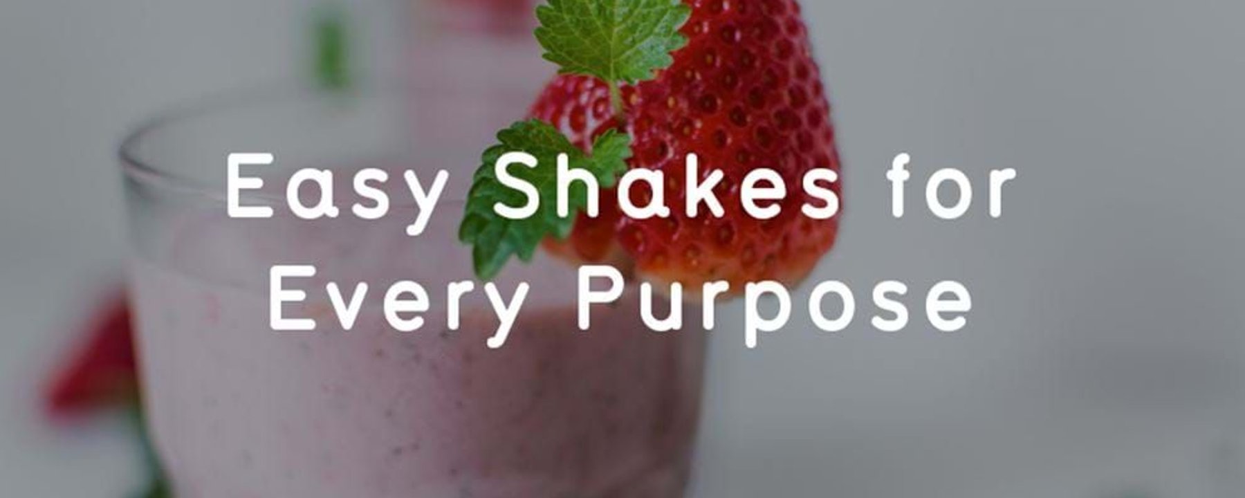 Strawberry milkshake in a glass garnished with a strawberry and a mint leaf