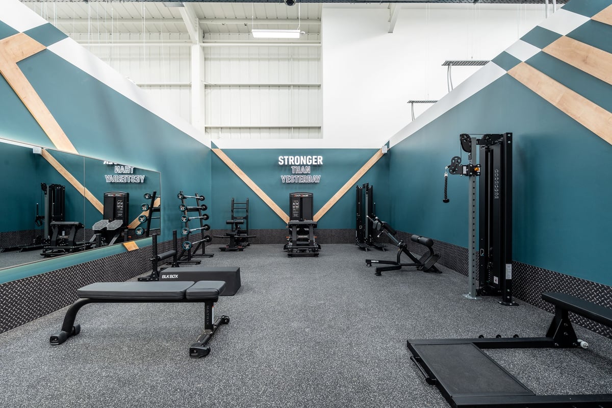 PureGym Keighley: Weightlifting equipment, benches, racks, rubberized flooring in teal and peach colour scheme gym studio.