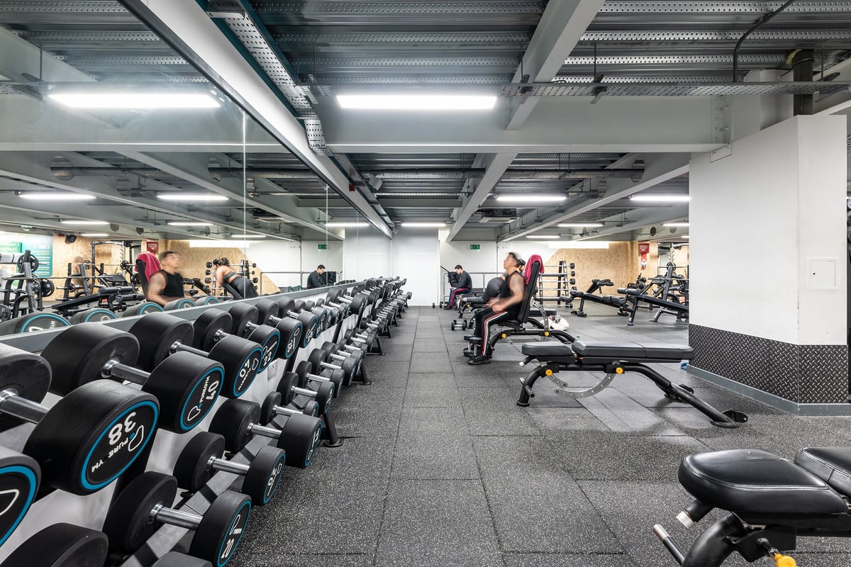 PureGym London Finsbury Park: Rows of stationary bikes, weight stacks, and rubberized floors in a brightly lit gym facility.
