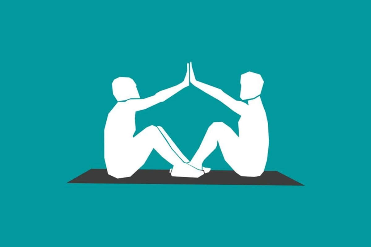 Two people sitting on a mat facing each other with hands touching in a high-five pose