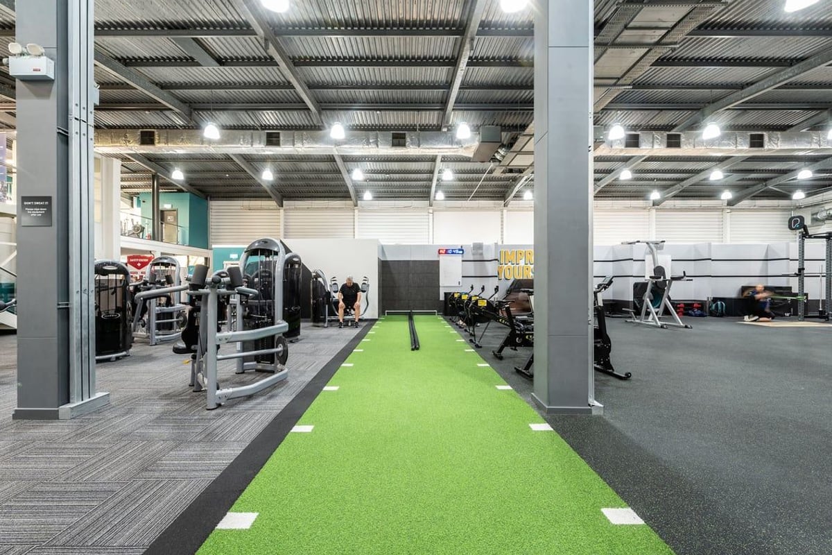 PureGym Milton Keynes Winterhill: Gym with turf runway, weightlifting platforms, machines, and rubberized flooring.
