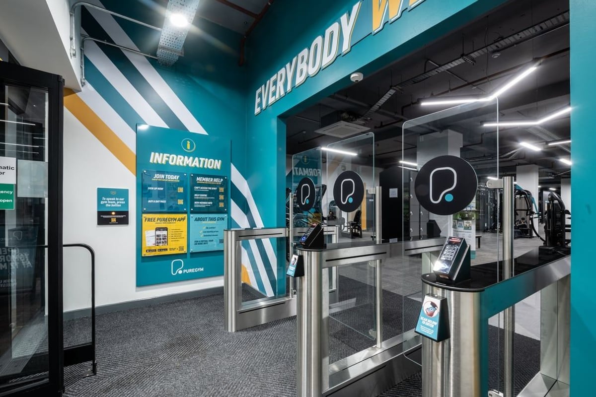 PureGym London Kingston: Turnstile entry area with body scanners, information screens, teal and black branding.