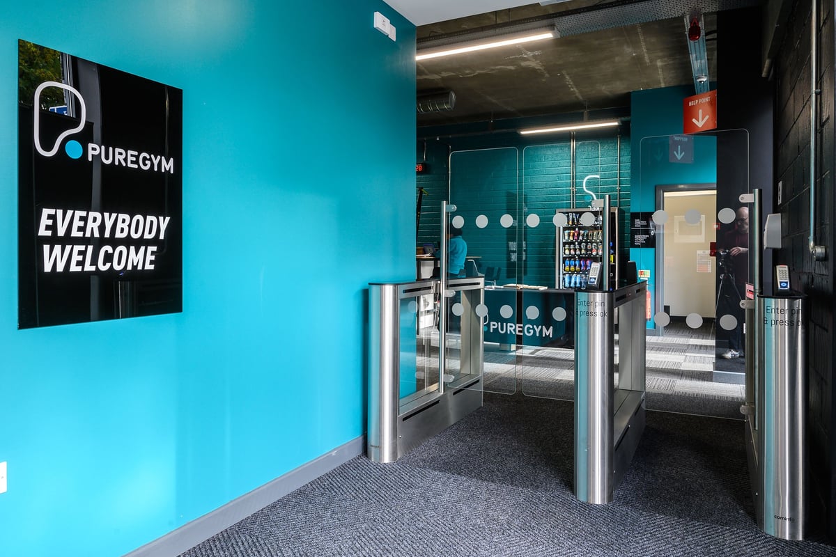 PureGym London Camberwell Southampton Way: Gym entrance with turnstiles, aqua branding, and "Everybody Welcome" signage.