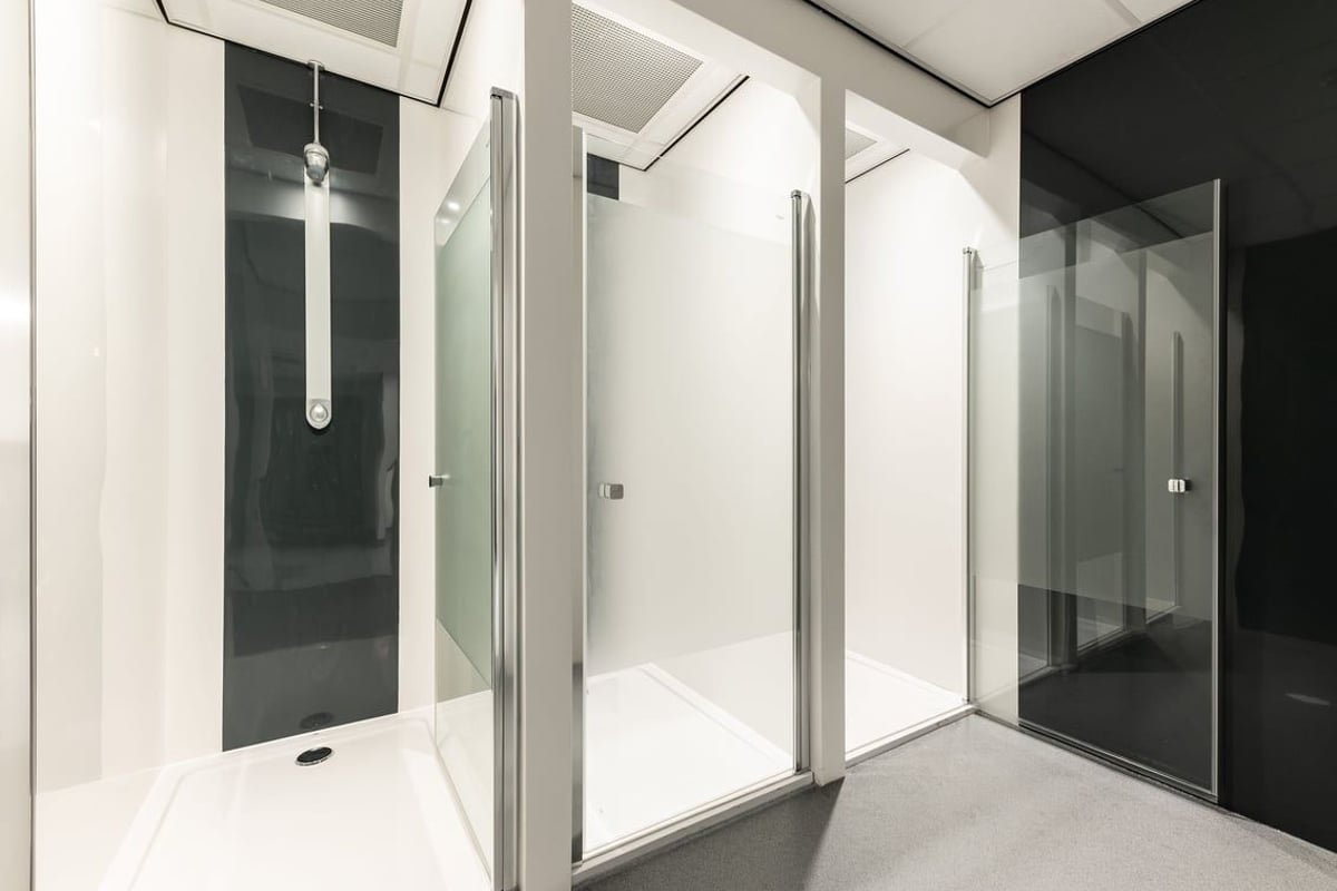 PureGym Kirkby: Shower cubicles with frosted glass doors and hanging shower heads.
