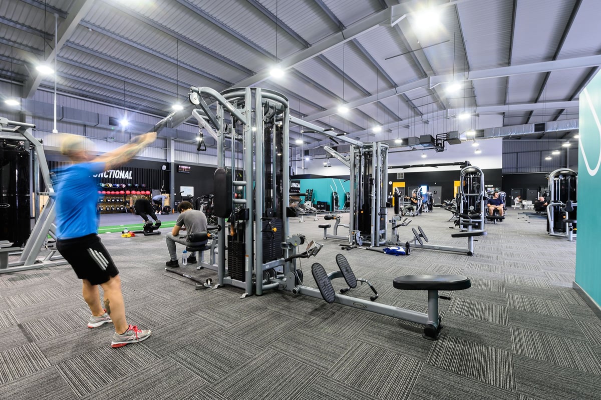 PureGym Widnes: Weight machines, free weights, benches, and weightlifting area inside a large gym facility.
