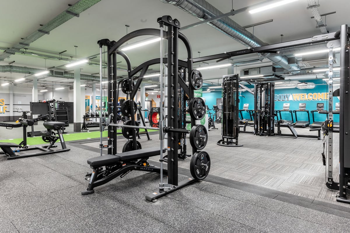 PureGym Milton Keynes Kingston Centre: Rows of strength equipment, including squat racks, benches, weight plates on racks.