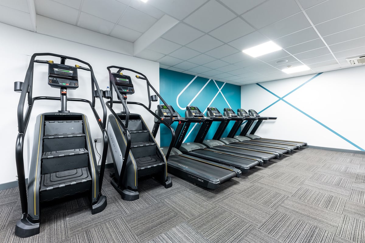 PureGym Luton And Dunstable: Rows of treadmills and elliptical trainers in a brightly lit fitness studio.