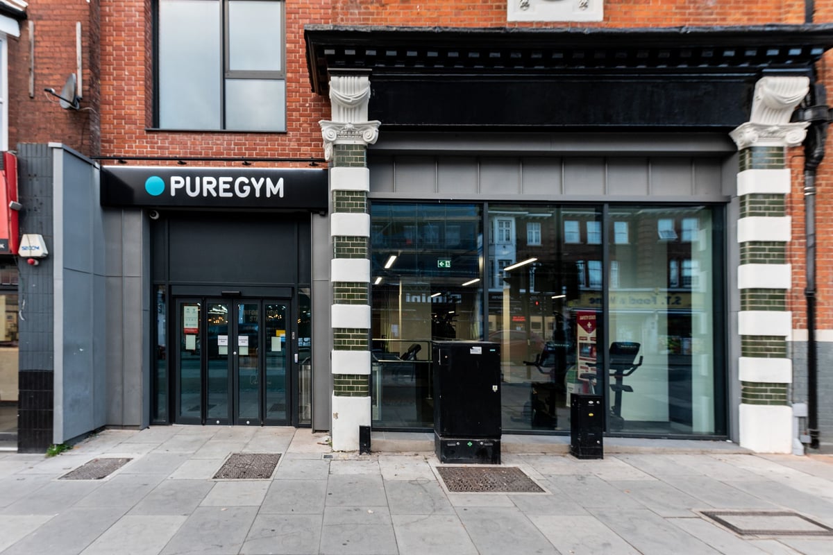 PureGym London Palmers Green: Pure Gym storefront with black facade, windows showcasing exercise equipment inside.