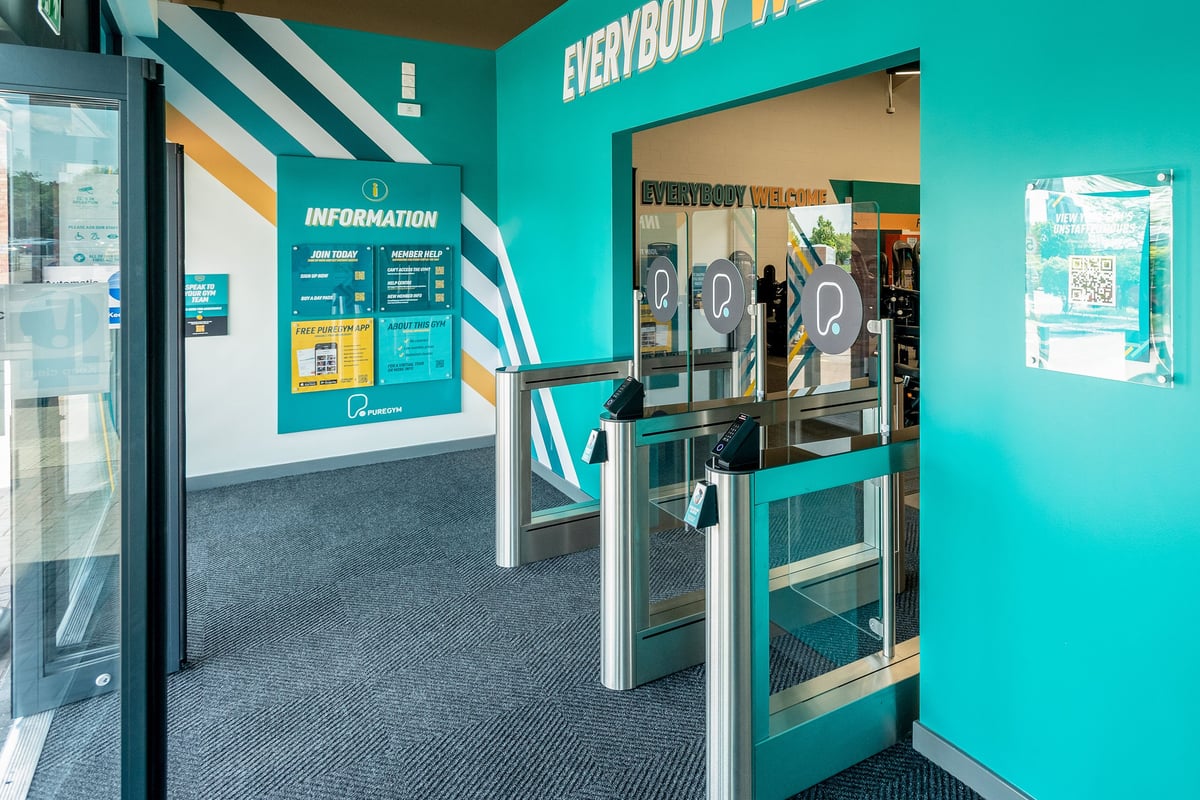PureGym Cannock Orbital Retail Park: Entrance area with turquoise walls, information desk, and self-service kiosks.