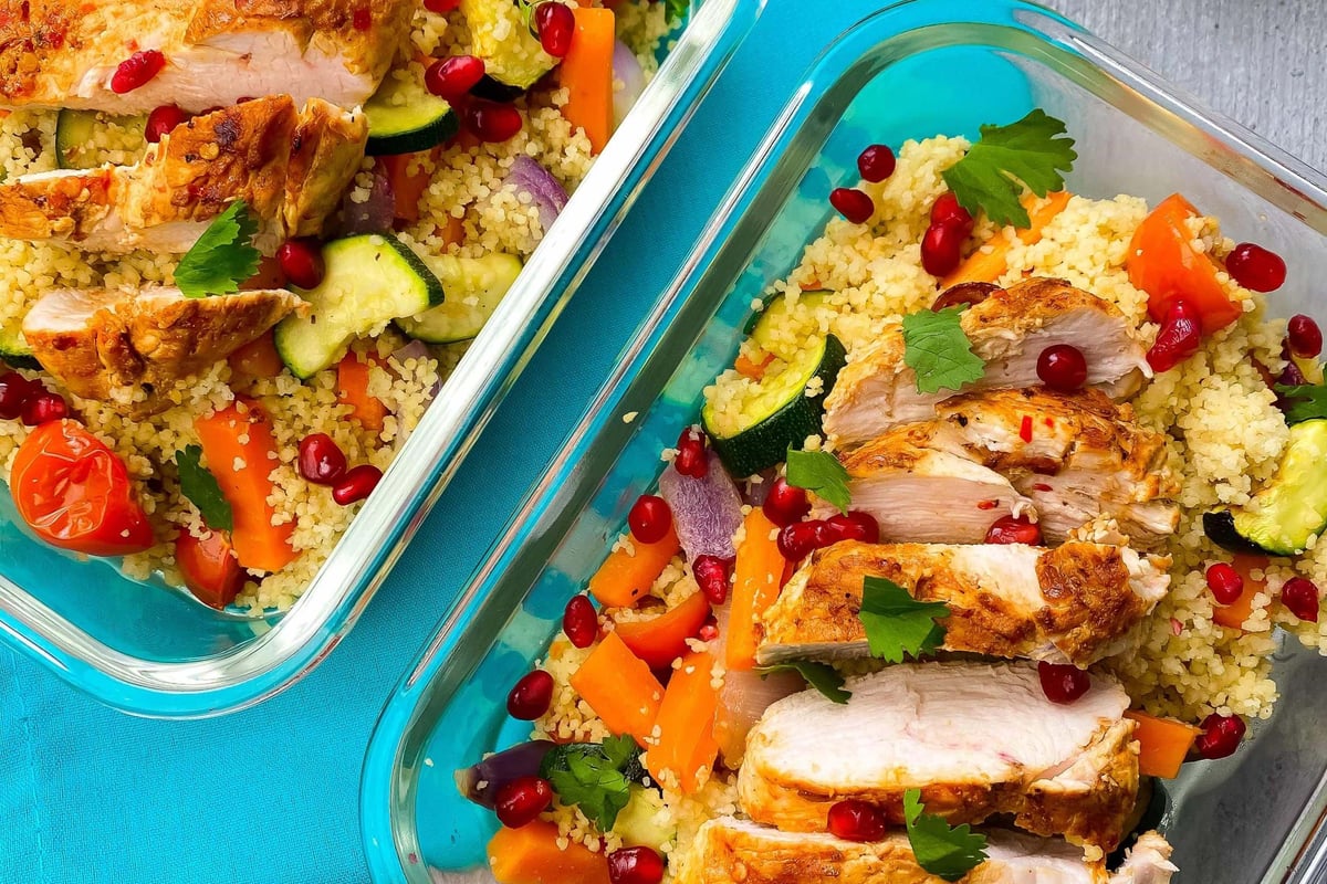 Grilled chicken slices on couscous with vegetables and pomegranate seeds