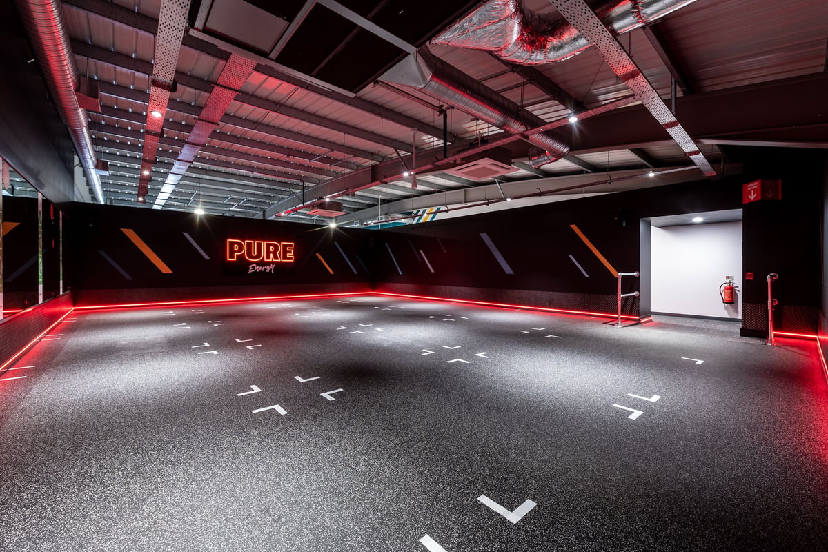 PureGym Bournemouth Mallard Road Retail Park: Fitness studio with red accent lighting and rubberised flooring.