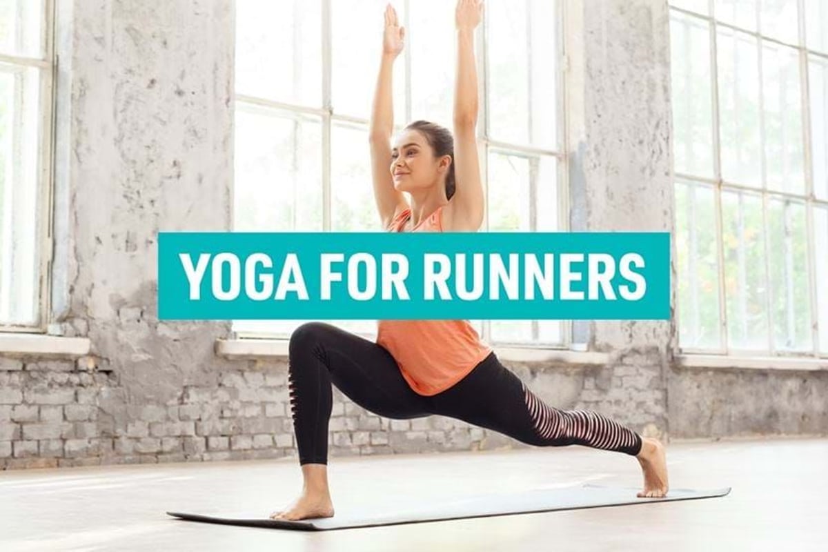 Woman in orange top and black leggings doing yoga lunge pose indoors