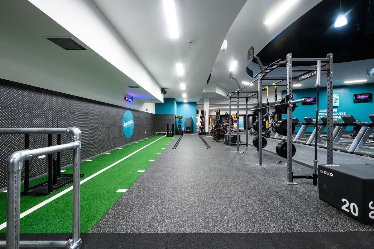 PureGym Northampton Central: Strength training area with squat racks, turf sections, weights, rigs, and rubberized floors.