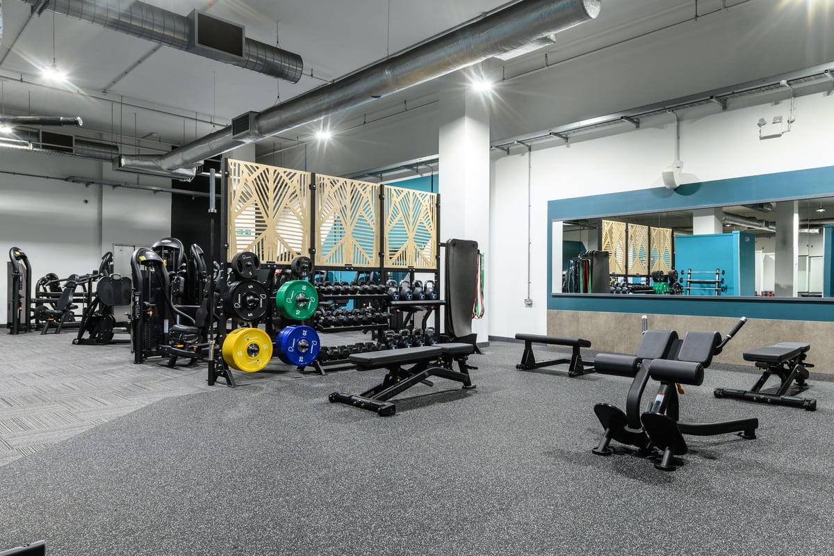 PureGym East Kilbride: free weights and benches in a gym against a mirrored wall