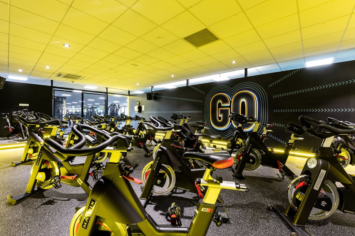 PureGym Livingston: Rows of yellow stationary exercise bikes arranged in an indoor gym facility.