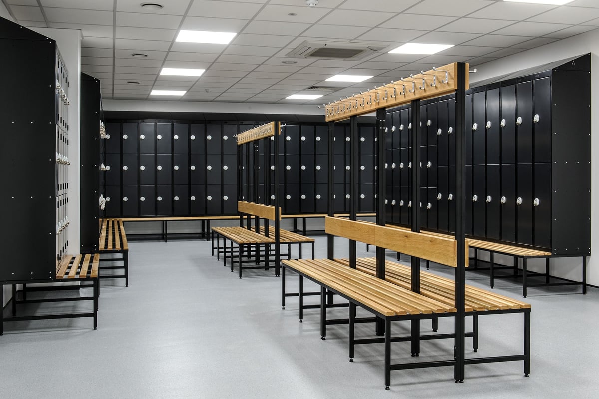 PureGym Woking: Locker room benches, black metal lockers lining the walls.