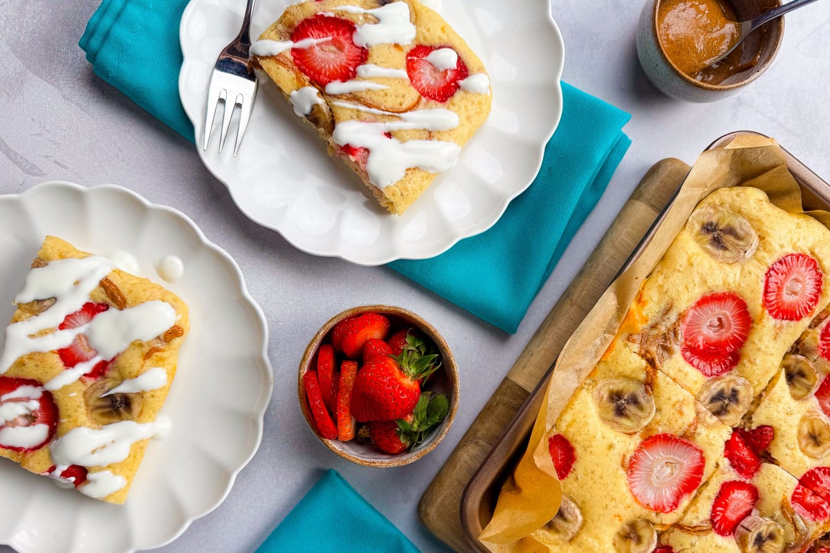 Sliced banana and strawberry traybake served on plates with white icing drizzle